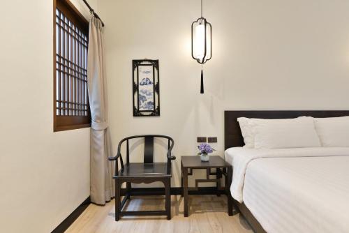 a bedroom with a bed and a chair and a window at Oldthaiheng Hotel in Bangkok