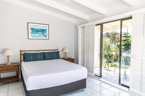 a bedroom with a bed and a balcony at Beachfront Terraces with Onsite Reception & Check In in Port Douglas