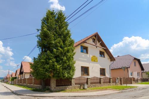 a large tree in front of a white house at Ubytovanie Zuzana in Smižany
