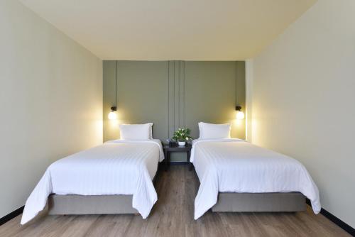 two beds in a room with white sheets at Oldthaiheng Hotel in Bangkok