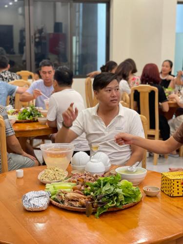 a woman sitting at a table with a plate of food at Đồi Chè Hotel in Mộc Châu