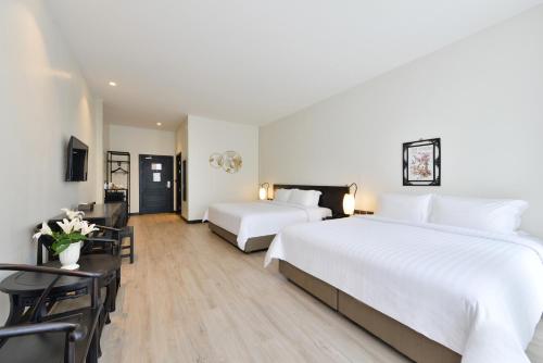 a hotel room with two beds and a table and chairs at Oldthaiheng Hotel in Bangkok