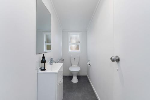 a white bathroom with a toilet and a sink at The Middle in Rotoiti