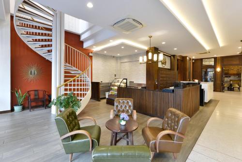 a lobby with a staircase and chairs and a table at Oldthaiheng Hotel in Bangkok