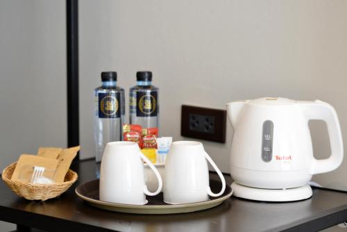 a coffee maker and cups on a table at Oldthaiheng Hotel in Bangkok