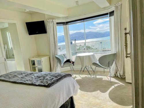 a bedroom with a bed and a balcony with a table and chairs at Incredible Views! Luxurious Studio & Outdoor Living in Wellington