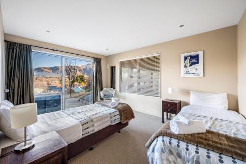 a bedroom with two beds and a large window at Criffel Garden Apartment in Wanaka