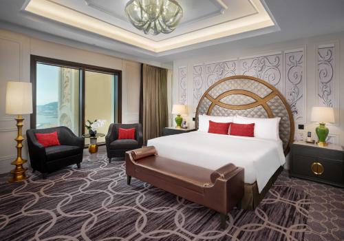 a hotel room with a large bed and two chairs at THE KARL LAGERFELD in Macau