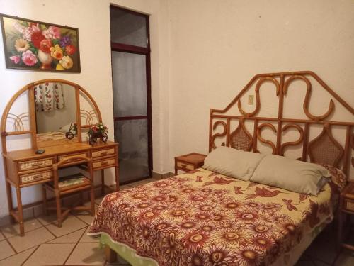 1 dormitorio con cama, escritorio y espejo en La Fortaleza, en Tonatico