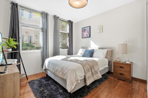 a white bedroom with a bed and a window at Sunny Bondi Retreat: Beach & Culture Unite! in Sydney