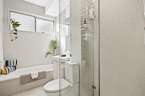 a bathroom with a toilet and a glass shower at Sunny Bondi Retreat: Beach & Culture Unite! in Sydney