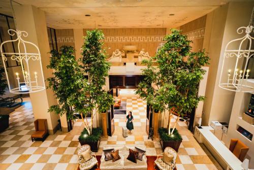 a woman walks through the lobby of a building with trees at Hotel Nikko Kanazawa in Kanazawa