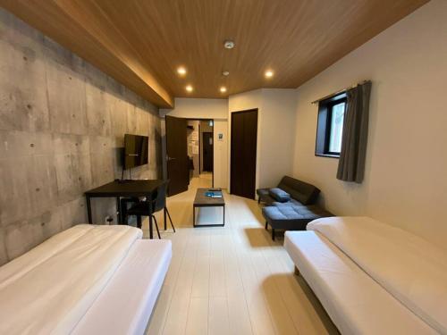 熊本市にあるリブレ in Kumamoto 302のベッド2台、ソファ、デスクが備わる客室です。