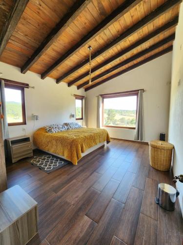 a bedroom with a bed and wooden floors and windows at Chalet Bosques de Zacatlan I in Zacatlán