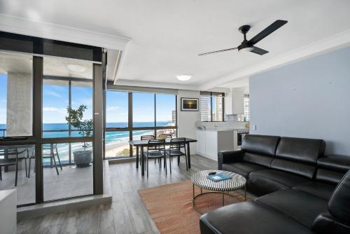 a living room with a black leather couch and a table at Capricorn One Beachside Holiday Apartments - Official in Gold Coast