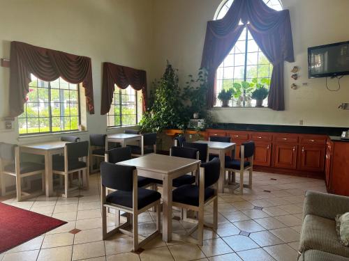 a dining room with tables and chairs and windows at Super 8 by Wyndham Stafford Sugarland Area in Stafford
