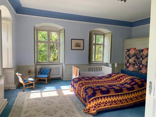 a bedroom with a bed and two windows and a chair at Wohnen im Wasserschloss Sandizell in Schrobenhausen