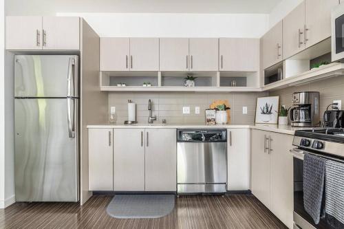 uma cozinha com armários brancos e um frigorífico de aço inoxidável em One bedroom luxury apartment (Gym, Wifi, Parking, Rooftop Deck) em Seattle