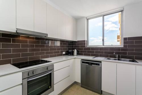 uma cozinha com armários brancos e uma janela em CRE31 - renovated 1 bedroom unit - Cremorne em Sidney