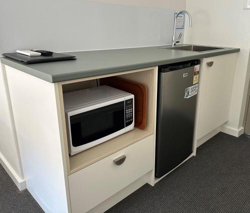a kitchen counter with a microwave and a sink at Golf View Motel in Sanctuary Point