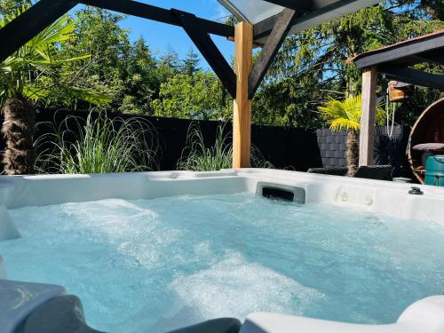 a hot tub in a backyard with a gazebo at Vakantiehuis de Heide in Bergen op Zoom