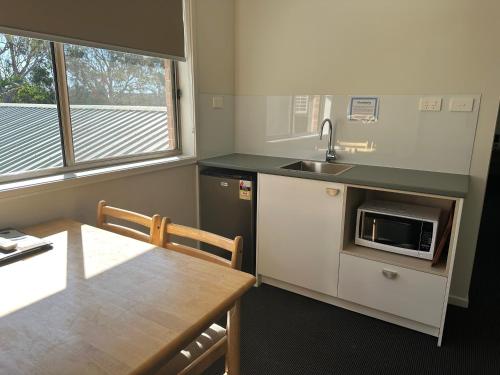 a kitchen with a table and a sink and a microwave at Golf View Motel in Sanctuary Point