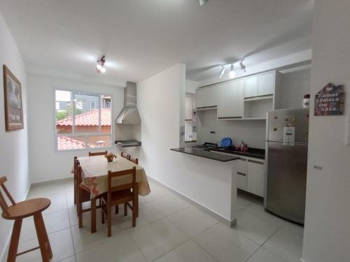 uma cozinha branca com uma mesa e um frigorífico em Apartamento Jardim das Palmeiras II - Ubatuba em Ubatuba
