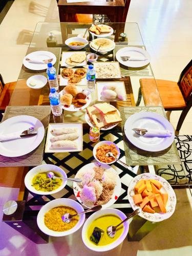 a table topped with plates and bowls of food at Gold Crown Residence in Dambulla