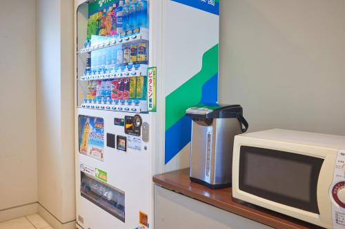 a refrigerator with many drinks and a microwave at RJ Hotel Naha in Naha
