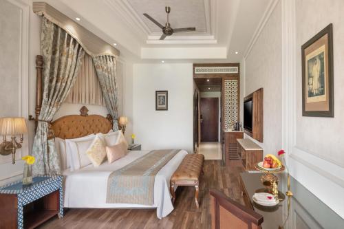 a bedroom with a large bed and a desk at Noormahal Palace Hotel in Karnāl