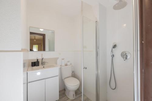 a white bathroom with a toilet and a shower at Desert Pearl in Beer Sheva