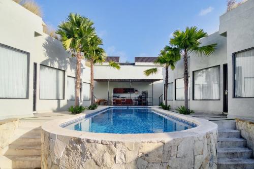 a swimming pool in front of a house with palm trees at KAYA Uluwatu in Uluwatu
