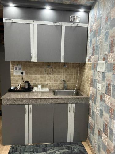 a kitchen with grey cabinets and a sink at The Origin Suites DLF MY PAD in Lucknow