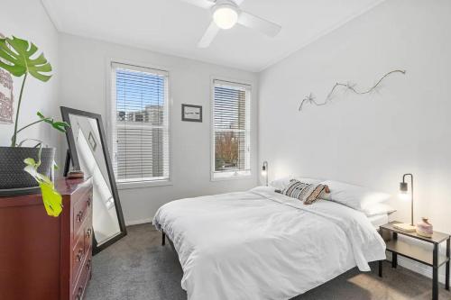 a white bedroom with a bed and a tv at Simply Kensington in Melbourne