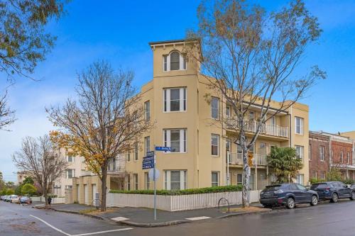 a yellow building with cars parked in front of it at Simply Kensington by Ready Set Stay in Melbourne