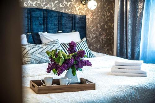 un vassoio con fiori viola e due tazze su un letto di THE BEST APARTMENT IN ŠIAULIAI 80sq m 14 floor a Šiauliai