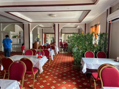 uma sala de jantar com mesas brancas e cadeiras vermelhas em CHINA STAR HOTEL em Kolonia