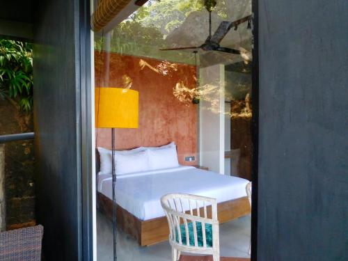a bedroom with a bed and a chair on a balcony at GlenMyu Estate in Haputale