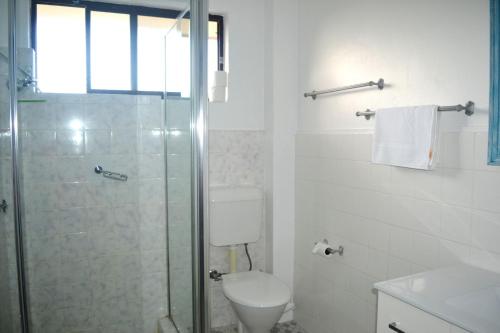 a bathroom with a toilet and a glass shower at Village Centre 6 in South West Rocks