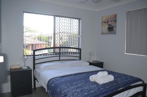 a bedroom with a bed with two towels on it at Village Centre 6 in South West Rocks