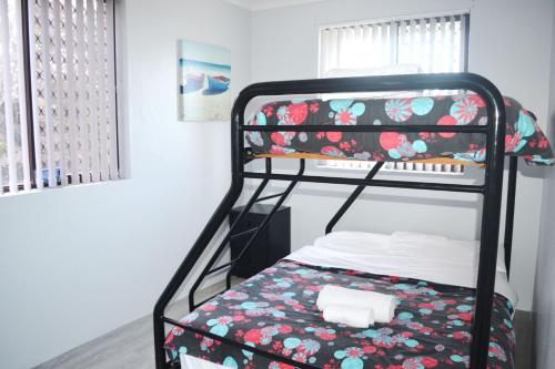 a bedroom with a bunk bed with a floral blanket at Village Centre 6 in South West Rocks