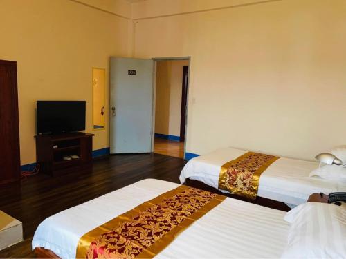 um quarto de hotel com duas camas e uma televisão de ecrã plano em CHINA STAR HOTEL em Kolonia