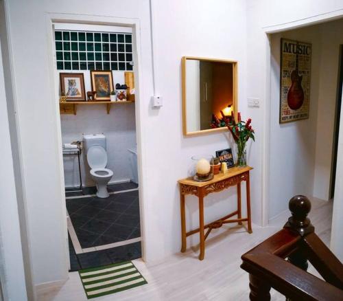 a bathroom with a toilet and a table with a mirror at Family Holiday House @Civic Centre Dewan Suarah in Sibu