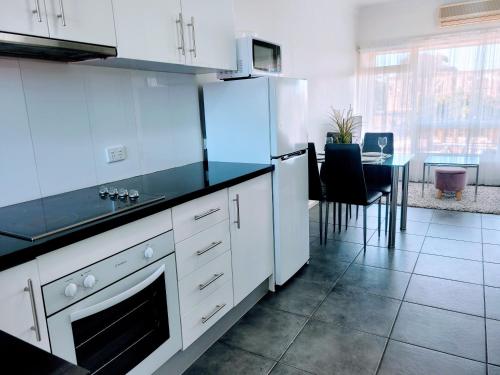 a kitchen with white cabinets and a black counter top at Zig Zag at Henley ~ BEACH ~ DINING ~ WiFi ~Airport in Henley Beach South