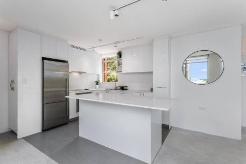 a white kitchen with a sink and a mirror at HAR20 - 2 bedroom Harrison Street - Cremorne in Sydney
