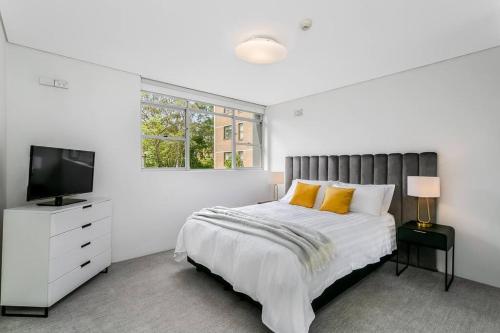 a white bedroom with a bed and a television at HAR20 - 2 bedroom Harrison Street - Cremorne in Sydney