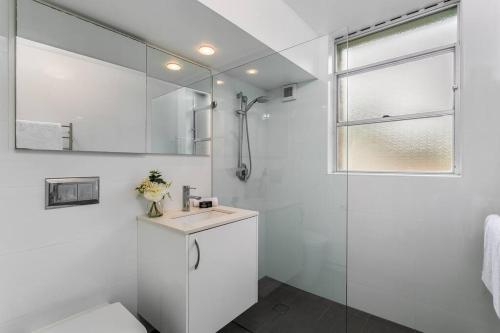 La salle de bains blanche est pourvue d'une douche et d'un lavabo. dans l'établissement HAR20 - 2 bedroom Harrison Street - Cremorne, à Sydney