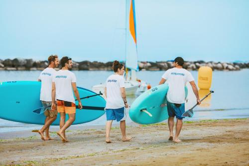 a group of men walking on the beach with surfboards at Hotel Albatros in Rimini