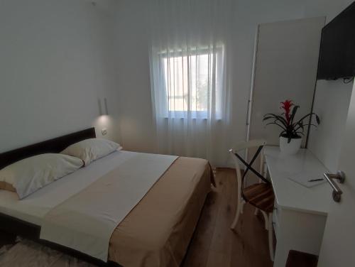 a bedroom with a bed and a desk and a window at Apartman Vlatka in Kninsko Polje