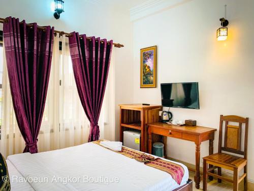 een slaapkamer met een bed, een bureau en een televisie bij Ravoeun Angkor Boutique in Siem Reap